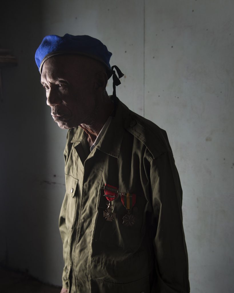 Kinshasa, République démocratique du Congo. Makengo Illenge. Né en 1936, dans la province du Bandundu. Policier formé par les Belges, il s’engage dans l’armée en 1959. Il commence ca carrière comme infirmier pour la force aérienne. En 1964, il est envoyé à Stanleyville (Kisangani) lors de la guerre contre les Simbas. Il participe ensuite à la première et à la deuxième guerre du Shaba (ancienne province du Katanga) de 1977 et 1978 lors desquelles les rebelles du FNLC (front national de libération du Congo) luttent contre Mobutu, avec le soutien de l’Angola et de Cuba. Il est ensuite envoyé à Beni, où il est nommé superviseur d’infirmerie. Il y restera trois ans avant de rejoindre sa femme et ses cinq enfants restés à Kinshasa, où il vit encore aujourd’hui. Interview réalisée le 22/11/2015.Portrait posé à son domicile.